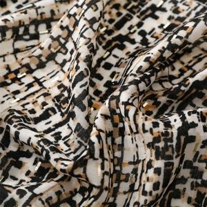 Detail of woven fabric with gold metallic threads and black geometric patterns on white base