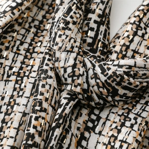 Macro detail of scarf fabric with tricolor geometric pattern and golden metallic threads