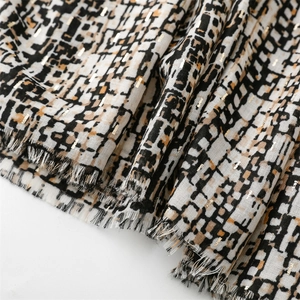 Detailed view of geometric plaid scarf fabric with gold threads and raw fringe edges