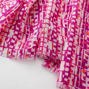 Close-up of lightweight pink scarf with woven gold metallic threads and geometric patterns