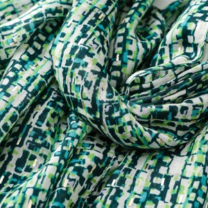Detail of green geometric pattern scarf with gold foil stripe and semi-transparent fabric