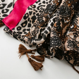 Detail of leopard print scarf with vibrant pink blocks and hand-woven fringe tassels