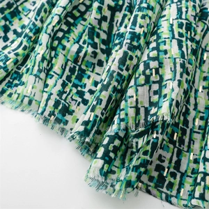 Close-up of green geometric pixel scarf with gold lurex threads and fringe edges