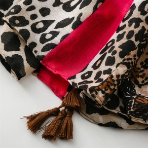 Detail of soft leopard print scarf with magenta stripe and dark brown fringe texture