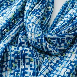 Macro shot of blue and white scarf with geometric mosaic prints and silver metallic details