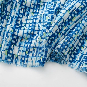 Detail of blue and white scarf featuring metallic foil accents and frayed tassel edges