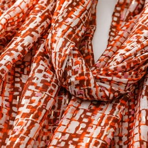 Detail of soft scarf featuring geometric grid pattern and shiny gold foil accents