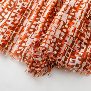 Close-up of geometric pattern scarf fabric with metallic gold accents and frayed edges