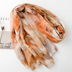 Detail of tie-dye gradient scarf featuring orange and brown tones with frayed edges
