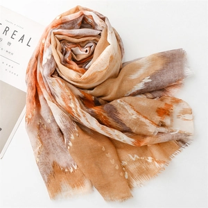 Detail of orange and brown abstract scarf with gold foil accents and frayed edges
