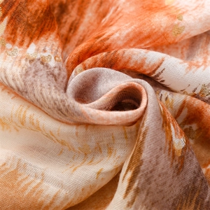 Detailed macro of soft scarf fabric with orange abstract print and gold foil dots