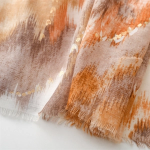 Detailed close-up of earth-tone linen scarf with golden heart foil and fringed edges