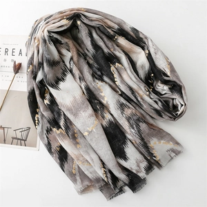 Detail of ikat pattern scarf with gold foil dots and natural frayed edges on white background