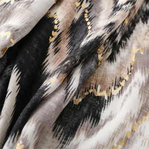 Detail of linen-feel scarf featuring golden heart patterns on a tie-dye texture background