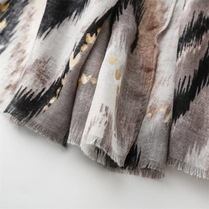 Detail of cotton linen scarf with golden heart prints and fringe edges on white backdrop