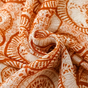 Detail shot of orange cotton linen scarf showing lotus mandala pattern and fabric texture