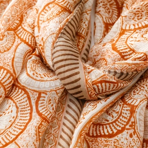 Detail of vintage orange mandala pattern scarf with fringe and soft linen texture