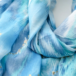 Detail of blue and white linen-touch scarf with gold foil mountain pattern and soft texture