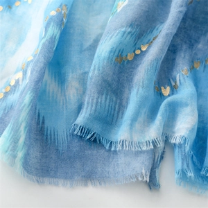 Close-up of blue gradient scarf with gold heart prints and fine tassel edges