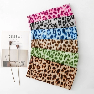 Detail view of multicolored leopard print cotton scarves layered on a white surface