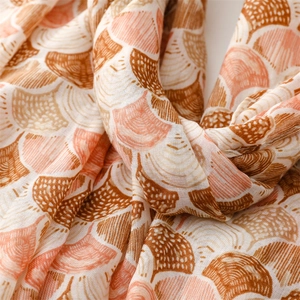 Detail of coral and beige seashell pattern scarf with soft linen-touch fabric texture