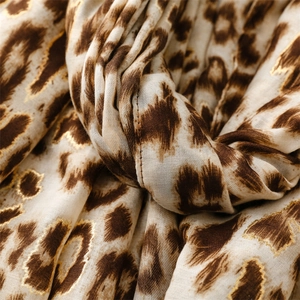 Close-up of leopard print scarf fabric featuring elegant gold foil detailing and texture