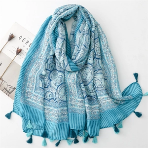Detailed flat lay of a blue floral linen scarf with fringe, magazine and dried flowers