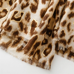 Macro detail of leopard print scarf featuring gold foil accents and fringe edges