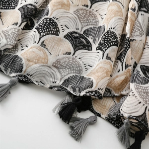 Detail view of woven cotton-linen scarf featuring a shell pattern with decorative tassels