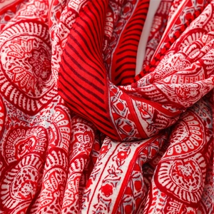 Detailed macro view of red and white floral patterned cotton linen scarf with tassels