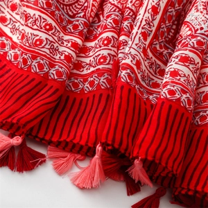 Close-up of ethnic red cotton linen scarf with floral patterns and delicate pink tassels