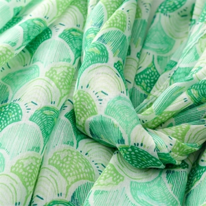 Macro shot of cotton linen scarf showing soft green shell patterns and delicate woven texture