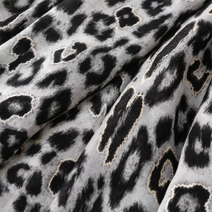 Macro shot of leopard print scarf fabric featuring metallic gold foil thread details
