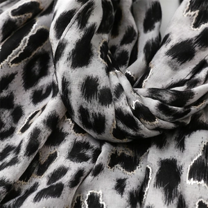Detail of leopard print scarf with metallic gold sequins on grey textured fabric