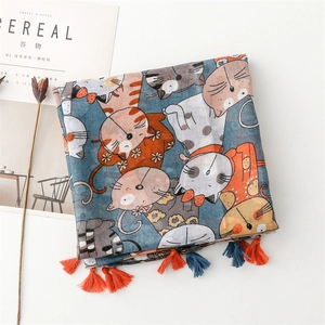 Détail de l'écharpe en coton et lin avec motifs de chats et pompons bicolores