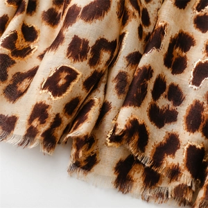 Detail of leopard print scarf featuring gold foil accents and soft fringed edges