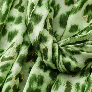Detailed macro view of green leopard print scarf fabric with fine gold metallic embroidery