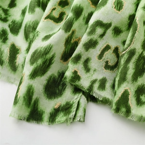 Detail of green leopard print scarf with golden foil outlines and frayed edges