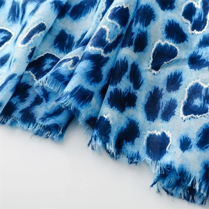 Detail of blue leopard print scarf with silver foil edges and raw fringe texture