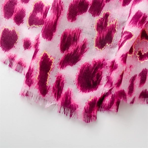 Detailed macro view of pink leopard print scarf fabric with golden glitter edges and fringe
