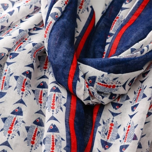 Gros plan de l'écharpe en coton avec motifs de poissons bleus et détails rouges