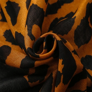Macro detail of leopard print scarf fabric showing soft twill texture and gradient hues