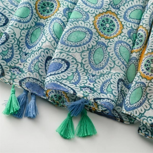 Macro shot of ethnic paisley print fabric with vibrant yellow and blue tassels