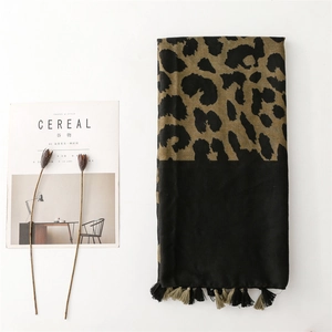 Detail shot of leopard print scarf with black fringe tassels on a minimalist background