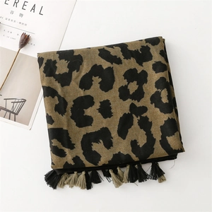 Detail shot of leopard print scarf with fringe tassels on white table with lifestyle props
