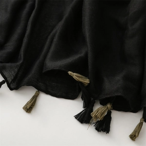 Macro detail of black semi-transparent scarf fabric with black and olive green tassels