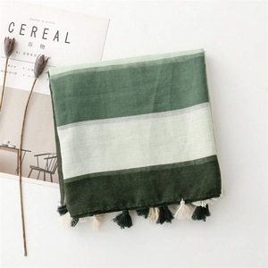 Detailed view of green striped cotton linen scarf with tassel fringe on white background