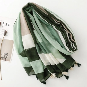 Lightweight green geometric striped scarf with tassels laid flat on a white surface