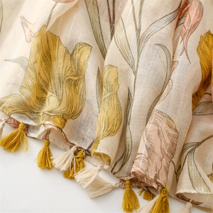 Detail of floral tulip print scarf with metallic silver stripes and yellow tassels