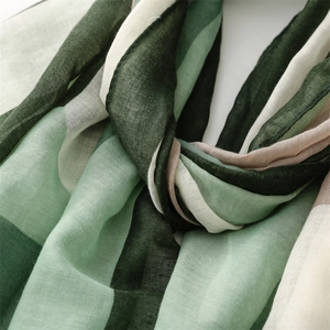 Detailed macro shot of green and white cotton linen scarf showing breathable fabric texture